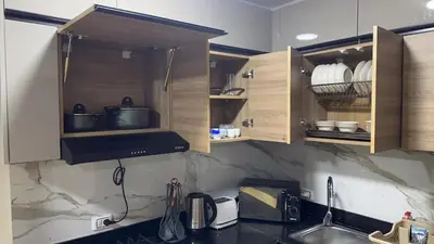 a kitchen with wooden cabinets and a sink at Serenity Cozy Studio Direct to the Pool In Hurghada in Hurghada