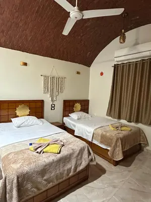 a bedroom with two beds and a ceiling fan at Nubian Soul Guest Houses in Aswan
