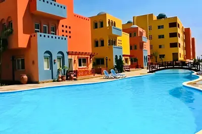 a swimming pool in a resort with colorful buildings at Amazing 2BR Apartment - Al Dora Resort, Hurghada in Hurghada