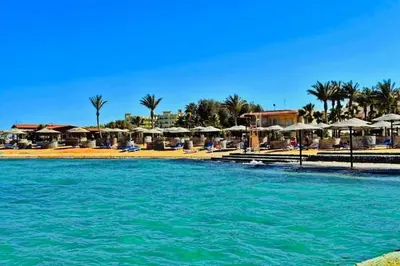 a pool of water with umbrellas and a resort at Amazing 2BR Apartment - Al Dora Resort, Hurghada in Hurghada