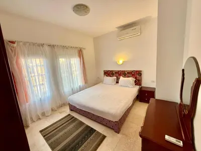 a bedroom with a bed with white sheets and a window at Amazing 2BR Apartment - Al Dora Resort, Hurghada in Hurghada