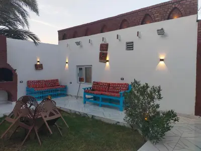 a patio with red and blue benches and chairs at Dolphin guest house in Jazīrat al ‘Awwāmīyah