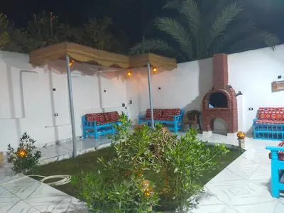a patio with blue benches and a fireplace at Dolphin guest house in Jazīrat al ‘Awwāmīyah