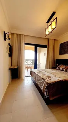 a bedroom with a large bed and a balcony at Cozy and spacious apartment for family , view sea in Hurghada