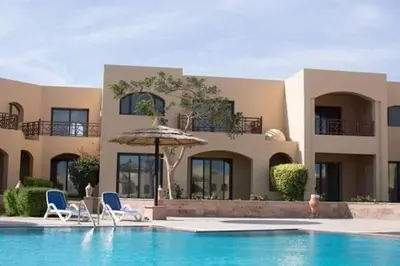 a house with a swimming pool with chairs and an umbrella at Cozy and spacious apartment for family , view sea in Hurghada