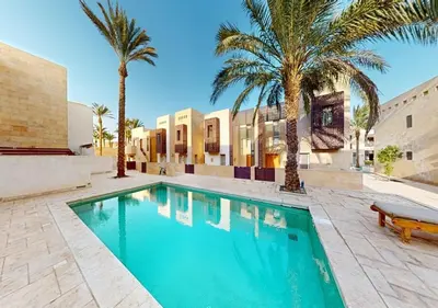 a swimming pool with palm trees in front of a building at Stylish 1 Bedroom at Scarab - El-Gouna WS14 in Hurghada