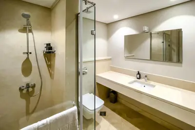 a bathroom with a shower and a toilet and a sink at Radiant & Refined 2BDR MangroovyFree Beach & Pool in Hurghada