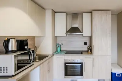 a kitchen with white cabinets and a stove top oven at Radiant & Refined 2BDR MangroovyFree Beach & Pool in Hurghada