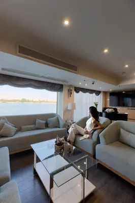 a woman sitting on a couch in a living room at Acamar Nile Cruise - Every Monday from Luxor for 04 & 07 Nights - Every Friday From Aswan for 03 & 07 Nights in Luxor