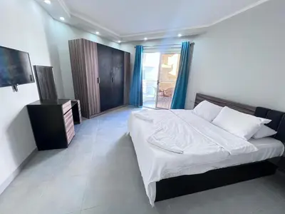 a bedroom with a large white bed with blue curtains at سكانديك ريزورت - Scandic resort in Hurghada