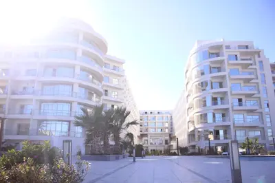 two tall white buildings with palm trees in front of them at سكانديك ريزورت - Scandic resort in Hurghada