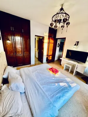 a large white bed in a bedroom with a chandelier at 2Bedroom in west golf in Hurghada