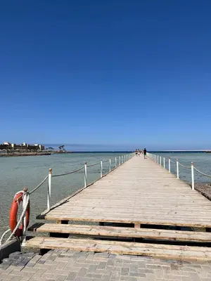 a wooden pier with a boat on the water at Scandic resort hurghada in Hurghada