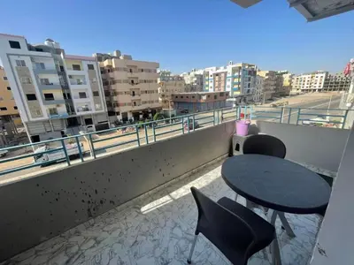 a table and chairs on a balcony with a view of a city at Hurghada Concierge at St Paul building 3 bd in Hurghada