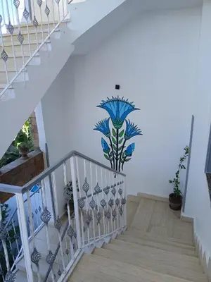 a staircase with a mural of a plant on the wall at Nile Rose Hause in Al Karnak