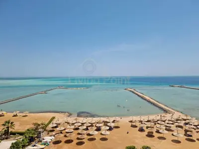 a beach with umbrellas and people in the water at Turtles beach resort ED Seaview Apartment in Hurghada