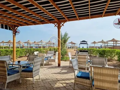 a patio with chairs and tables and umbrellas on the beach at Turtles beach resort ED Seaview Apartment in Hurghada