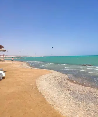 a sandy beach with a few chairs and the ocean at Fanadir Bay Resort, rental chalet apartment in Hurghadana in Hurghada