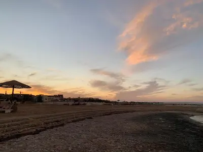 a sunset on a beach with an umbrella and chairs at Fanadir Bay Resort, rental chalet apartment in Hurghadana in Hurghada