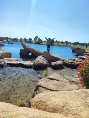 a man standing on rocks in front of a body of water at Soma Breeze Sea and Golf view in Hurghada