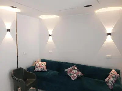 a living room with a green couch and lights at white popular apartment in Al Karnak
