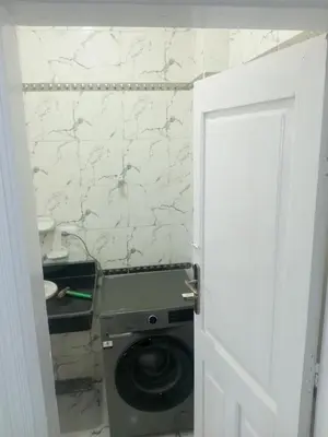 a washing machine in a bathroom with a stone wall at white popular apartment in Al Karnak