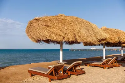 a group of chairs and umbrellas on a beach at Sunrise Solara Aqua park Resort in Banī Ghālib