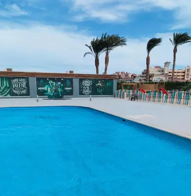 a blue swimming pool with palm trees in the background at Scandic Resort Hurghada in Hurghada