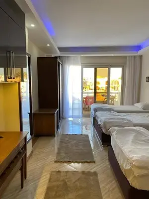 a hotel room with three beds and a table at سيسليا بيتش ريزورت in Hurghada