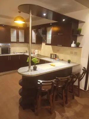a kitchen with a counter with chairs around it at , كمبواند قمريه in Hurghada