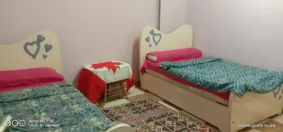 a small bedroom with two beds and a table at Al Agamay Nile view guest House in Jazīrat Aswān