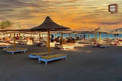 a beach with chairs and umbrellas and the ocean at Relaxing apartment in Hurghada