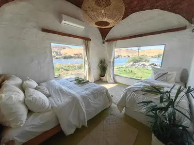 a bedroom with two beds and a large window at Nala Narty Nubian House & Organic Farm in Aswan