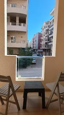 a balcony with two chairs and a table and a window at Cozy studio Florenza Khamsin in Hurghada