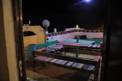 a room with a table and benches at night at Carmah Nubian Guesthouse in Aswan