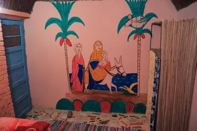 a mural on the wall of a room with palm trees at Carmah Nubian Guesthouse in Aswan