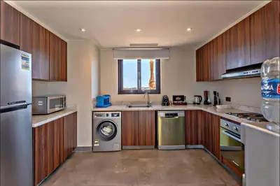 a kitchen with wooden cabinets and a washer and dryer at inchant sands elgouna luxury villa in Hurghada