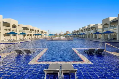 a swimming pool at a resort with chairs and umbrellas at Albatros Makadi Resort - 24 HRS All Inclusive in Hurghada