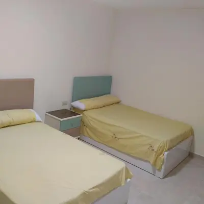 a small room with two beds and a chair at Golden Tayeb Hurghada Compound in Hurghada