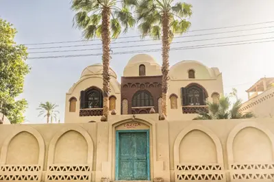 a building with a green door and palm trees at Laziza in Luxor