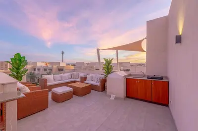 a rooftop patio with furniture and a view of the city at Coastal Vibe 2BR Mangroovy Gouna with Rooftop Cinema, BBQ, Pool & Beach Access in Hurghada