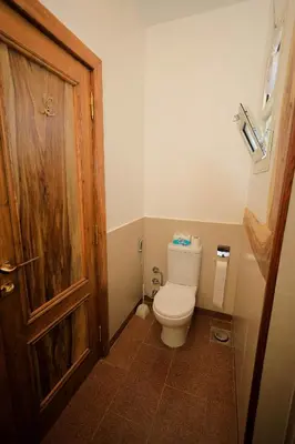 a bathroom with a toilet and a wooden door at Kaya Nubian House in Aswan