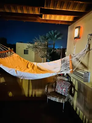 a hammock on a balcony with a chair and a window at شاليه في ستيلا مكادي الغردقة in Hurghada