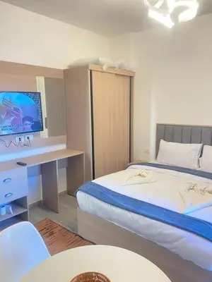 a bedroom with two beds and a desk with a television at Studio pool view at Imperial Resort Hurghada in Hurghada