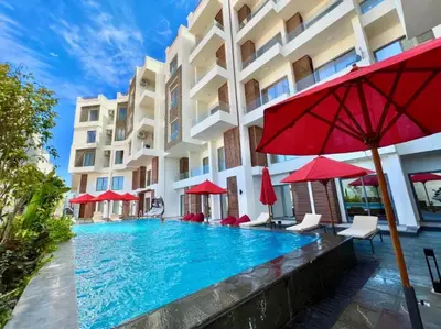 a pool in front of a building with red umbrellas at Studio pool view at Imperial Resort Hurghada in Hurghada