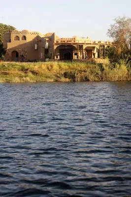 a house sitting on the side of a body of water at Shalal Farm and guest house in Aswan