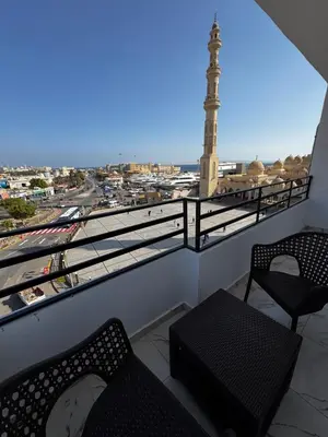a balcony with two chairs and a view of a mosque at Seaside Serenity Apartment in Hurghada