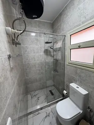 a bathroom with a toilet and a glass shower at Seaside Serenity Apartment in Hurghada