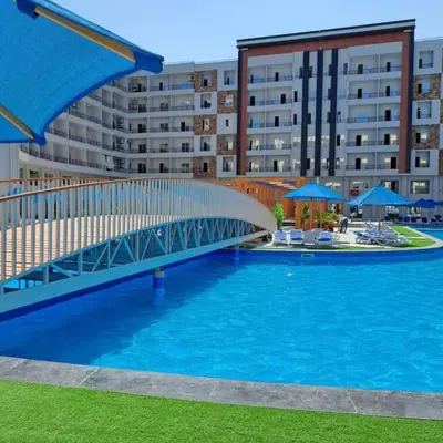 a bridge over a swimming pool in front of a building at Tiba Golden a in Hurghada
