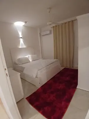 a bedroom with a white bed and a red rug at Nopian 1 in Luxor